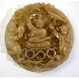 A Chinese circular jade applique carved with a reticulated design of three boys; one boy holding a