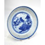 A Chinese blue and white dish of circular form with reticulated rim; decorated with a fisherman in a