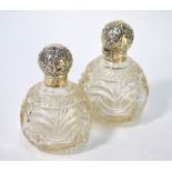 A late Victorian graduated pair of cut glass globular scent bottles, the hinged silver bun covers