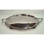 A large oval silver tray of lobed form with moulded rim and scroll-cast twin handles and four