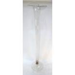 A tall floor standing glass vase in the form of an open lily, short metal stem and domed circular