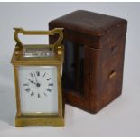 A brass carriage clock with single train 8-day movement and  white enamelled dial, the case engraved