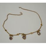 A Victorian gilt metal necklace hung with three heart shaped purple paste drops with half pearls