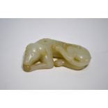 A Chinese modern, green jade figure of a recumbent hound with its head on its front paws, 9 cm long,