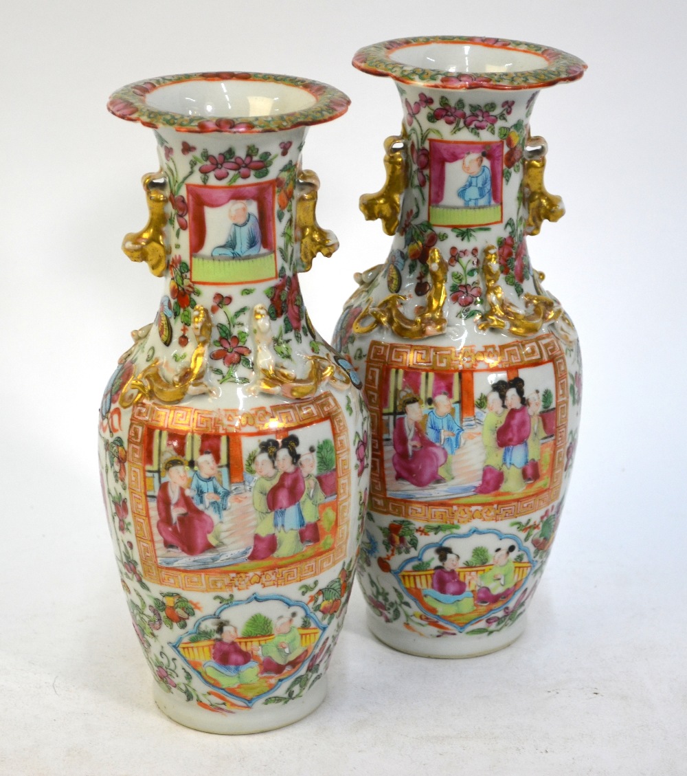 A pair of Canton famille rose vases; each one decorated with panels depicting Manchu/Chinese