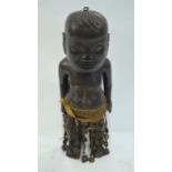 An ebonised tribal wood figure of a standing boy with both arms by his side; wearing a textile