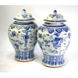 A pair of Chinese blue and white vases; each one with a domed cover and knop finial, decorated