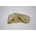 A Chinese modern, green jade figure of a recumbent hound with its head on its front paws, 9 cm long,