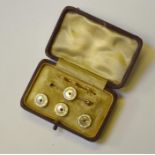 A cased set of mother of pearl and white enamel dress studs and pin, the centre set with small ruby,