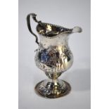 A George III silver baluster cream jug with beaded rim and scroll handle, embossed and chased with a