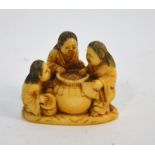 A Japanese ivory netsuke, carved as three Shojo, or other characters, standing beside a large sake