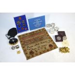 Four silver napkin rings, a Victorian needlework sampler, various military and Air Force brass