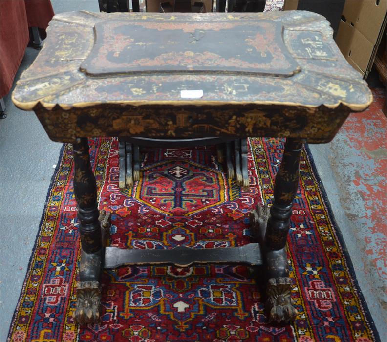 A Victorian gilt decorated black lacquered table with hinged top enclosing two lidded wells flanking