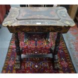 A Victorian gilt decorated black lacquered table with hinged top enclosing two lidded wells flanking