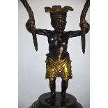 A parcel gilt twin branch candelabra supported by the figure of a young native boy, 36 cm high