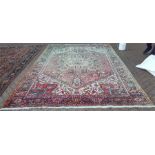 A Persian Heriz carpet with large central floral medallion on terracotts ground within guarded