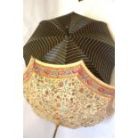 A 1920s floral printed woven cotton parasol, a black silk striped parasol with ebonised carved