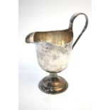 Guild of Handicrafts: a planished silver milk jug on stemmed foot, with scroll handle, London