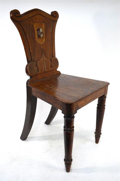 A Victorian mahogany hall chair, the moulded shaped back centred with a polychrome armorial raised