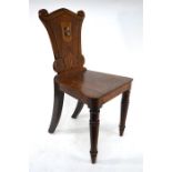 A Victorian mahogany hall chair, the moulded shaped back centred with a polychrome armorial raised