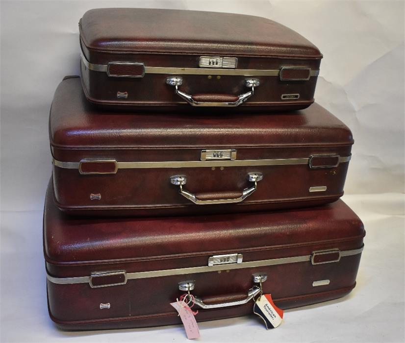 A graduated set of three vintage shadowed brown American Tourister suitcases with combination