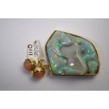 A pale green potch opal carved with two bears, set within an 18ct yellow gold textured and shaped
