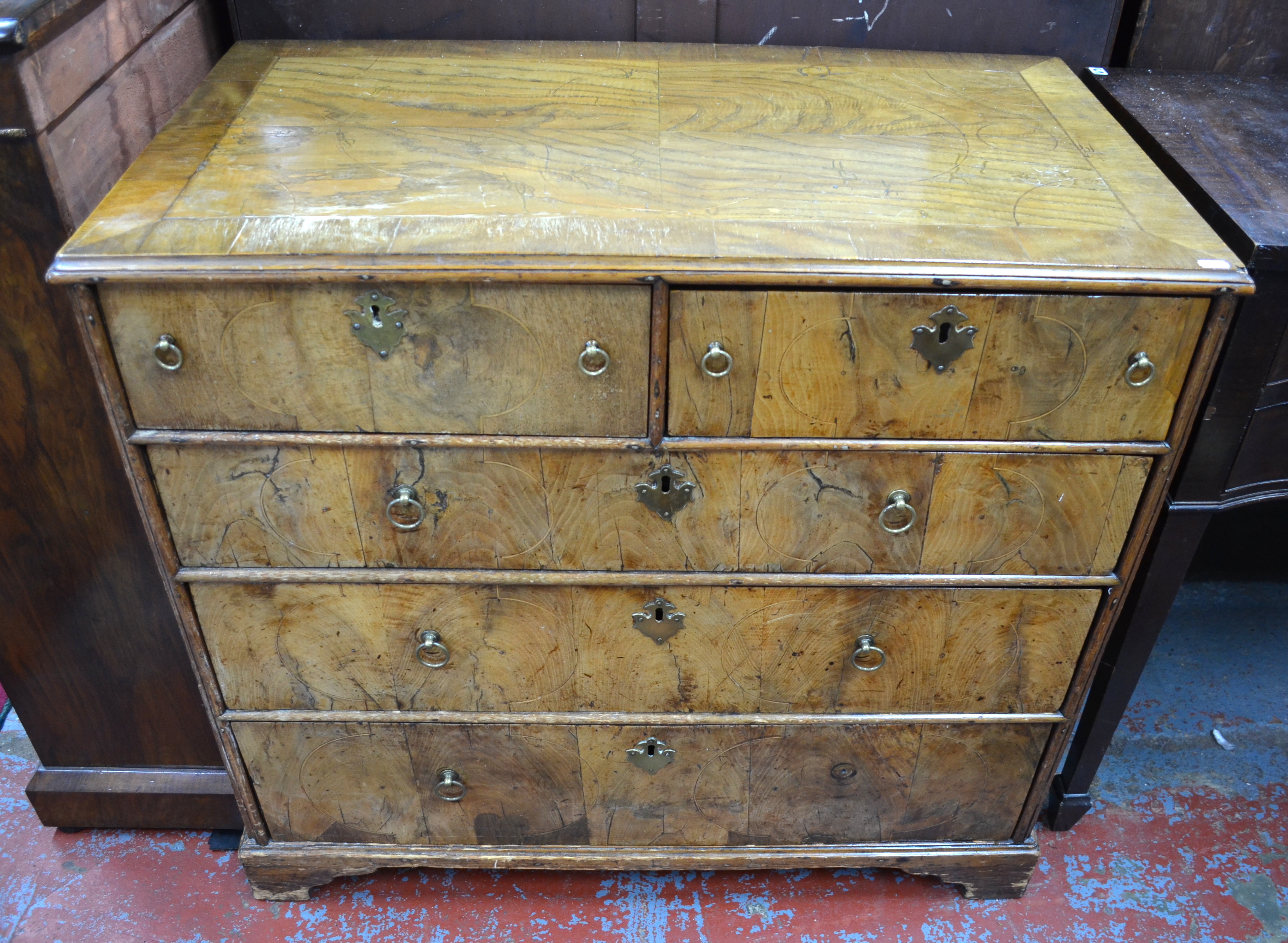 A late 17th century walnut chest of two short over three long graduated drawers, with brass ring