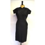 A 1950s black satinized cotton ribbed-effect dress with panelled bodice, belt, collar and hip side