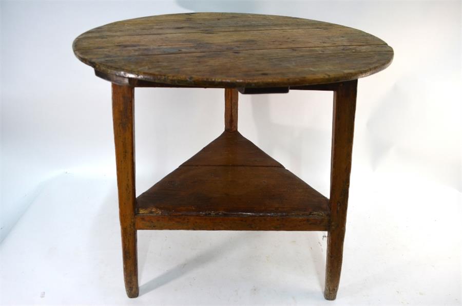 An 18th century pine cricket table, the circular plank top on chamfered square section legs united