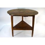 An 18th century pine cricket table, the circular plank top on chamfered square section legs united