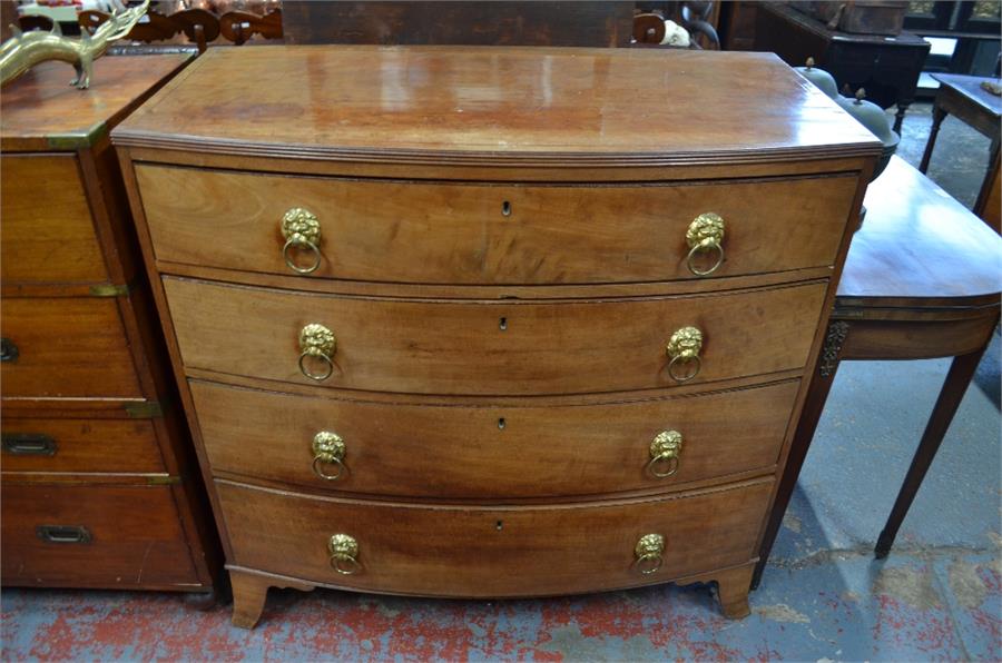 A 19th century bow front chest of four long graduated drawers with lion mask and ring handles,