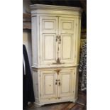 An antique painted pine cream two part standing corner cupboard, with two pairs of panelled doors
