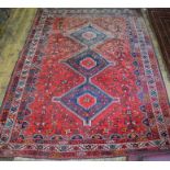 A Persian Shiraz carpet, the red ground with stylised centre medallion, 302 cm x 215 cm