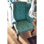 A George II style wing back armchair with brass studded green fabric raised on moulded cabriole