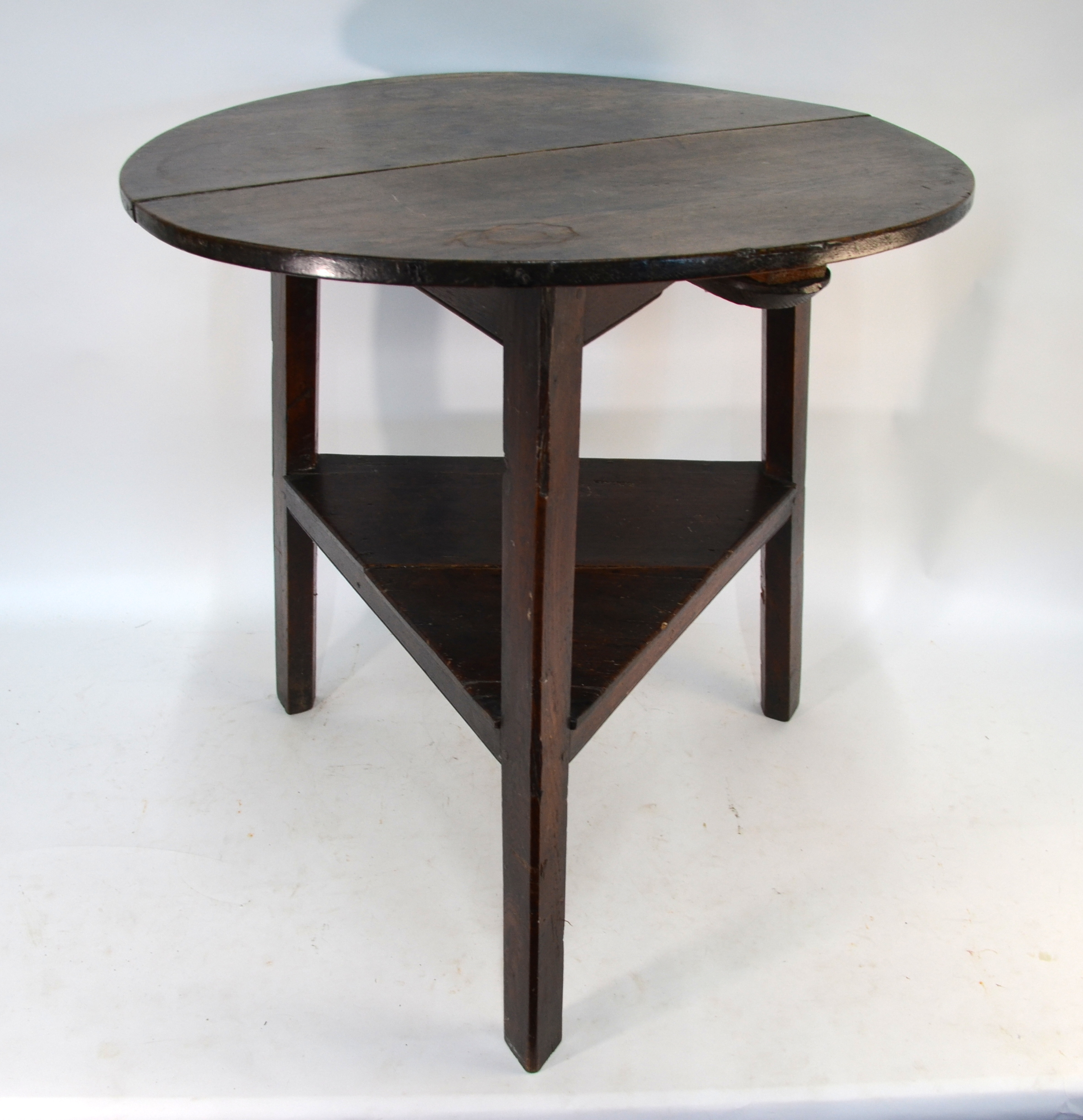 An 18th century oak cricket table, the two plank circular top raised on triangular legs united by