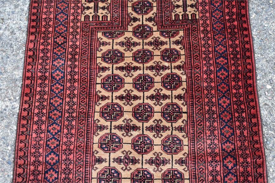 An Afghan Baluch prayer rug, circa 1900, the repeating gold design on a camel ground with - Image 2 of 3