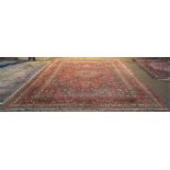 A Persian Dorokhsh carpet with large central rosette medallion on wine ground with floral design and