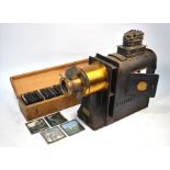 A lacquered brass and tin magic lantern, to/w a box of 59 slides including nursery tales and rhymes,