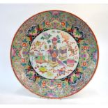 A famille rose circular dish, decorated with a central design of scholars implements and sacred