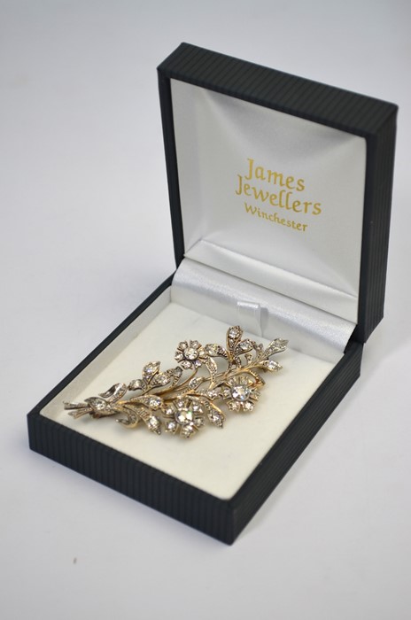 A diamond-set flower spray brooch formed of three flowers and foliage, the largest diamonds approx