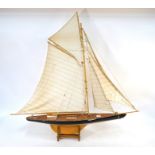 A wooden model of a J Class pond yacht, fully rigged, on stand, 120 cm wide x 120 cm high overall