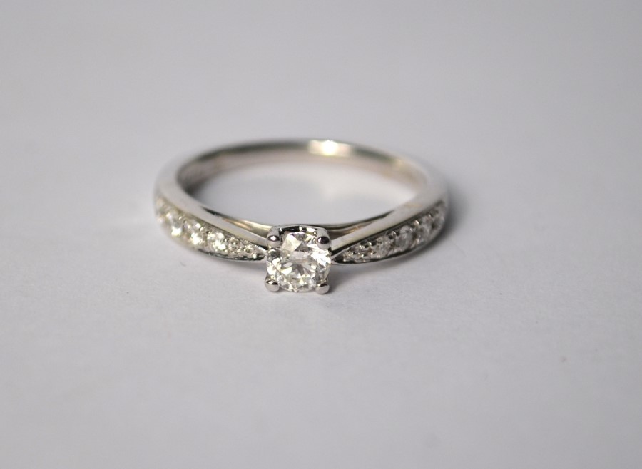 A contemporary 9ct white gold diamond ring, the central circular brilliant cut claw set diamond with