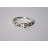 A contemporary 9ct white gold diamond ring, the central circular brilliant cut claw set diamond with