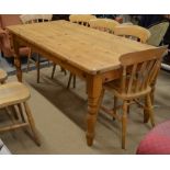 A stained pine kitchen dining table, the rectangular top raised on turned supports