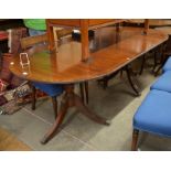 A Regency style mahogany and brass inlaid twin pedestal dining table with central leaf, turned