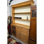 An antique stripped pine dresser base with central drawer and panelled cupboard doors to/w