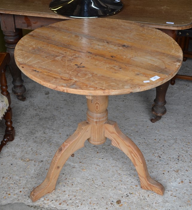 A stripped pine circular top occasional table on a turned column and triform support