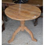 A stripped pine circular top occasional table on a turned column and triform support
