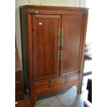 Oriental stained elm and brass mounted cupboard, the pair of panelled doors enclosing shelves and