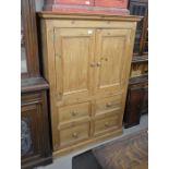 A waxed pine cupboard with panelled doors over four drawers raised on a plinth base 109 cm wide x 48